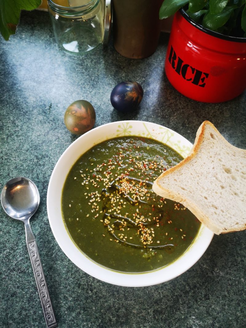 nettle soup in a white dish with a slice of bread