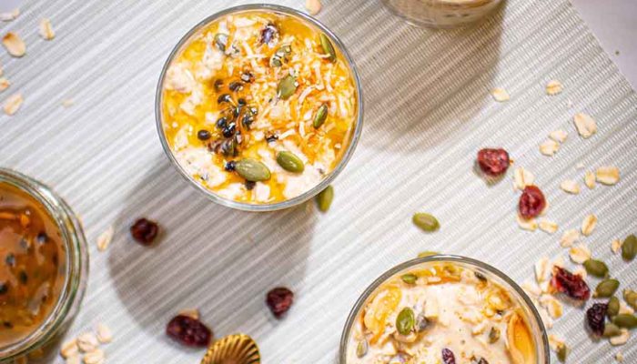 passionfruit overnight oats in a glasses on a table scattered with oats and berries