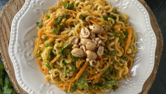carrot ginger noodles in a white dish with a brown and black background