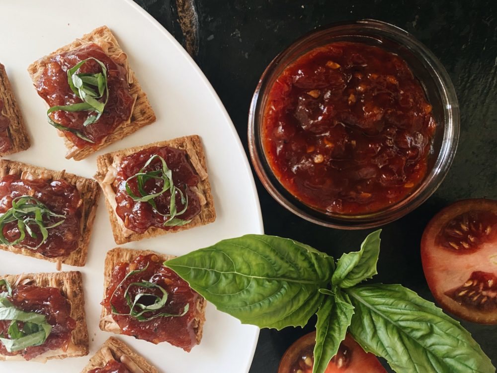 tomato balsamic jam in a jar and on crackers on a plate