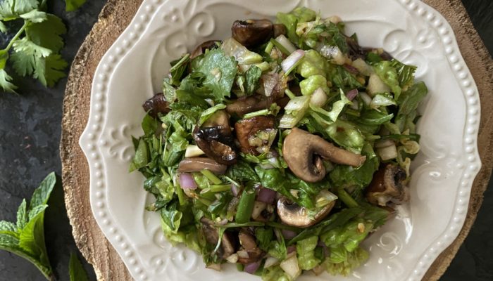 mushroom and herb salad on a white plate with brown and black background