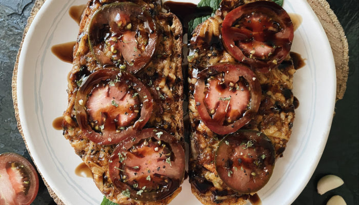 vegan cheesy tomato garlic bread on a white plate against a dark background