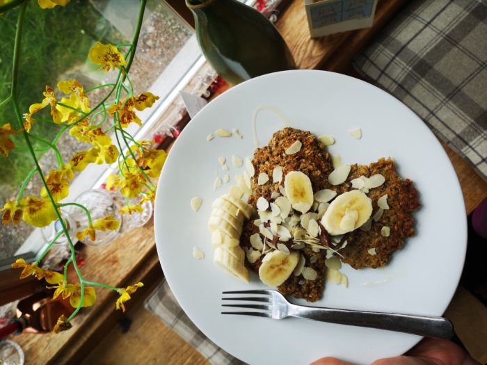 pancakes with banana slices on a white plate next to yellow flowers