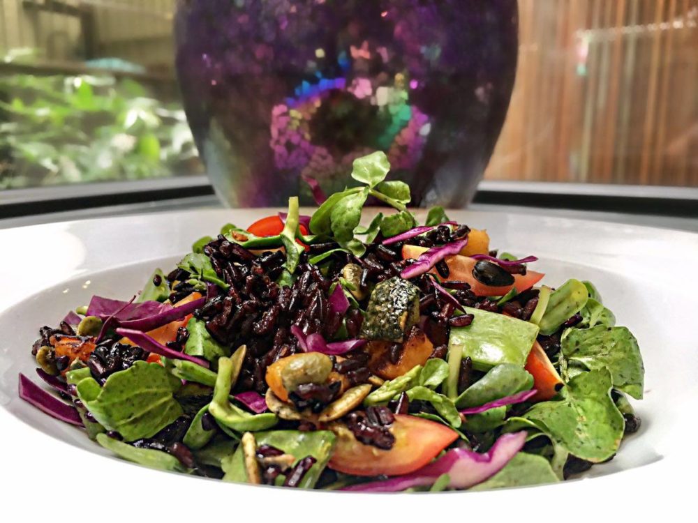 pumpkin and black rice salad with orange dressing in a white bowl