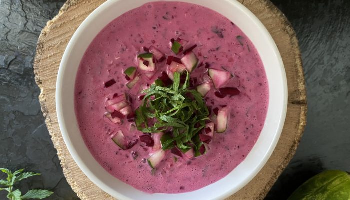 creamy cucumber beet dip in a white dish against a dark background