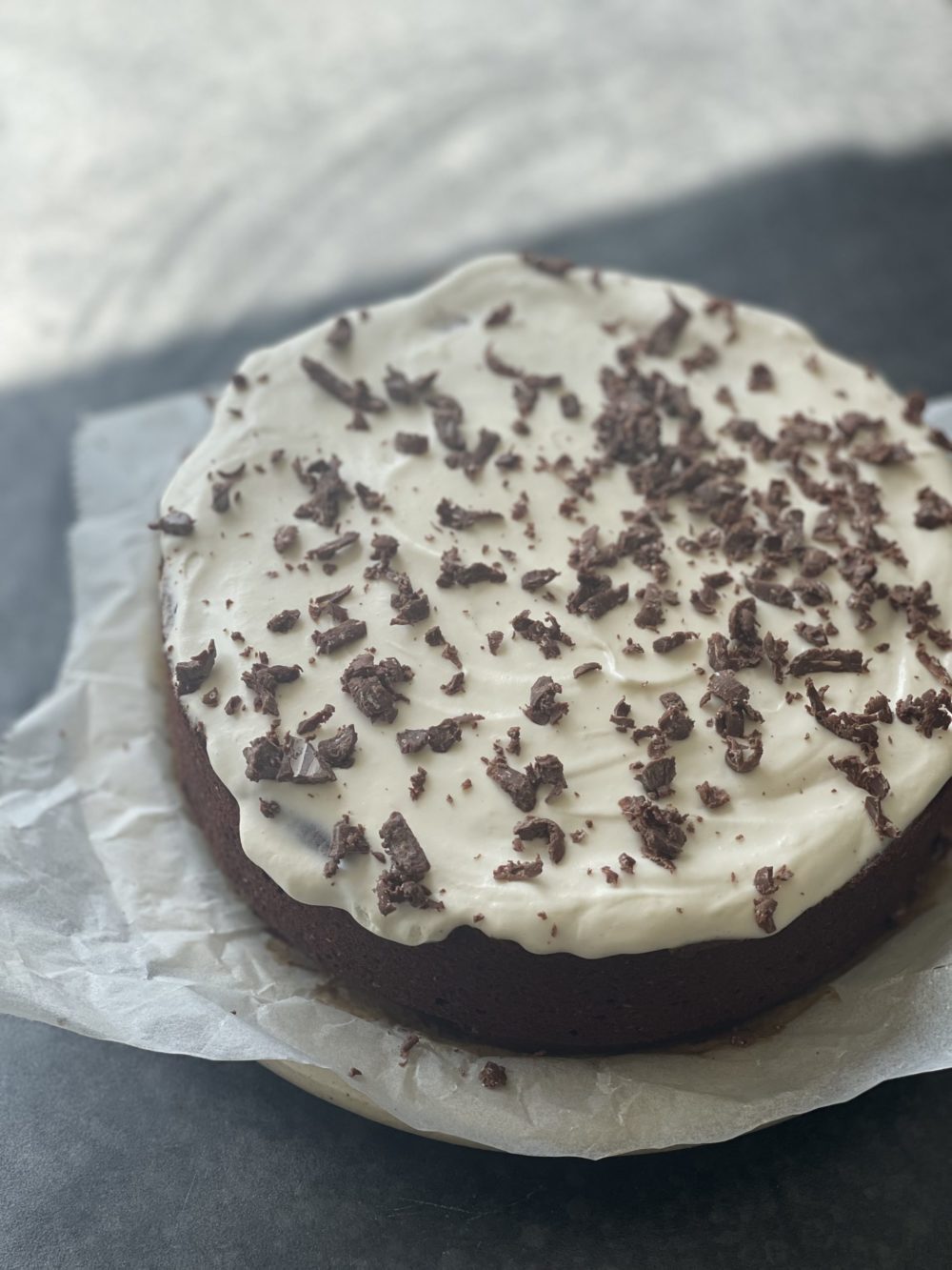 chocolate cake with white frosting on parchment paper