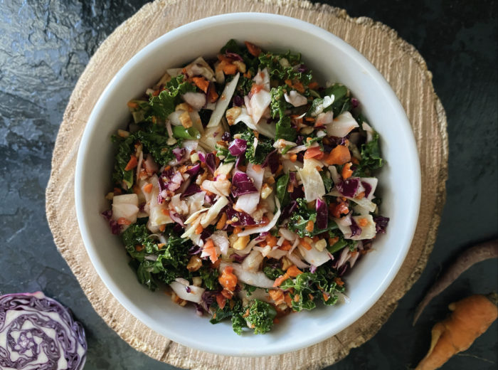 chopped asian salad in a white bowl against a brown and black background