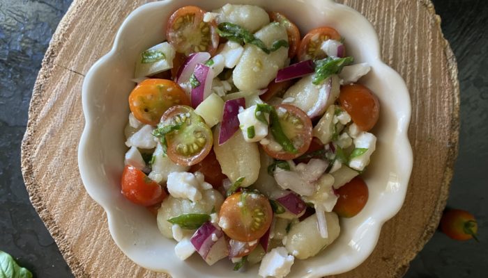 vegan gnocchi salad in a white dish against a brown and black background