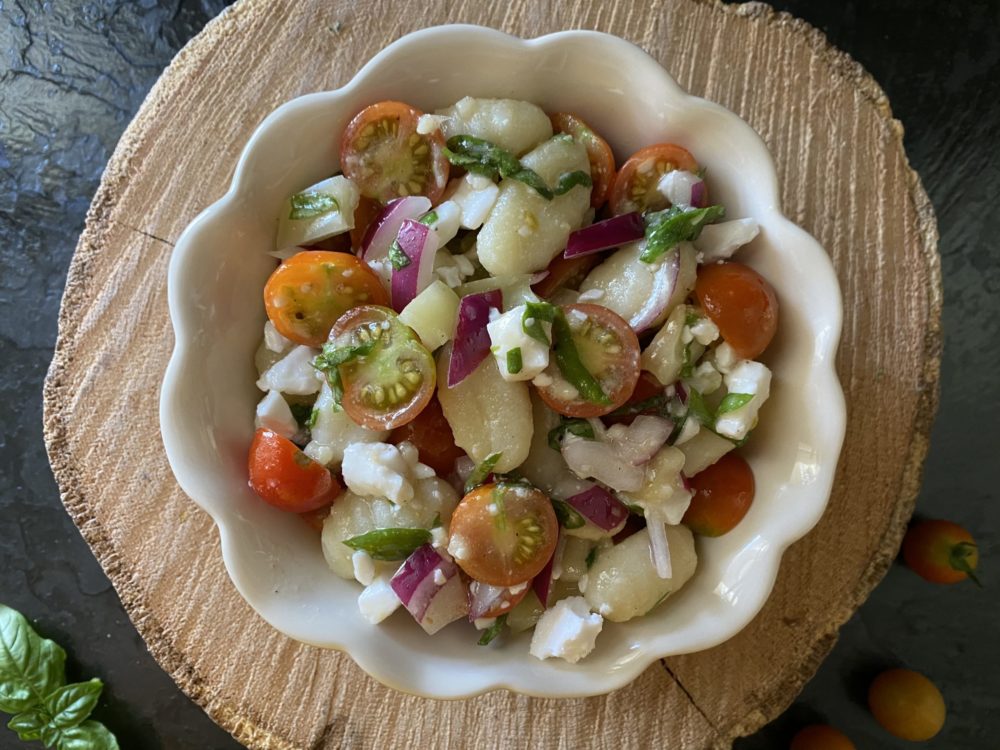 vegan gnocchi salad in a white dish against a brown and black background