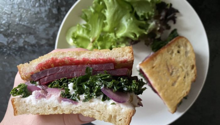 beet grilled cheese on a white plate against a dark background