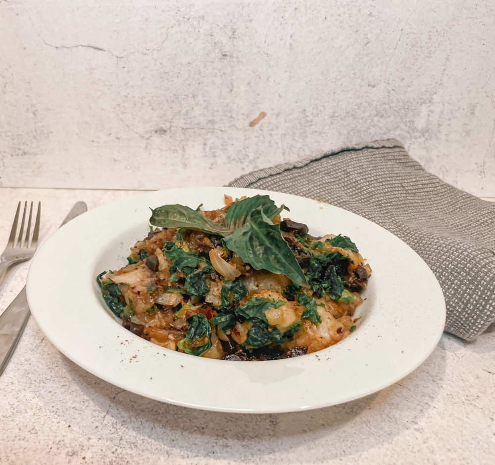 black garlic gnocchi on a white plate next to a gray towel and silverware