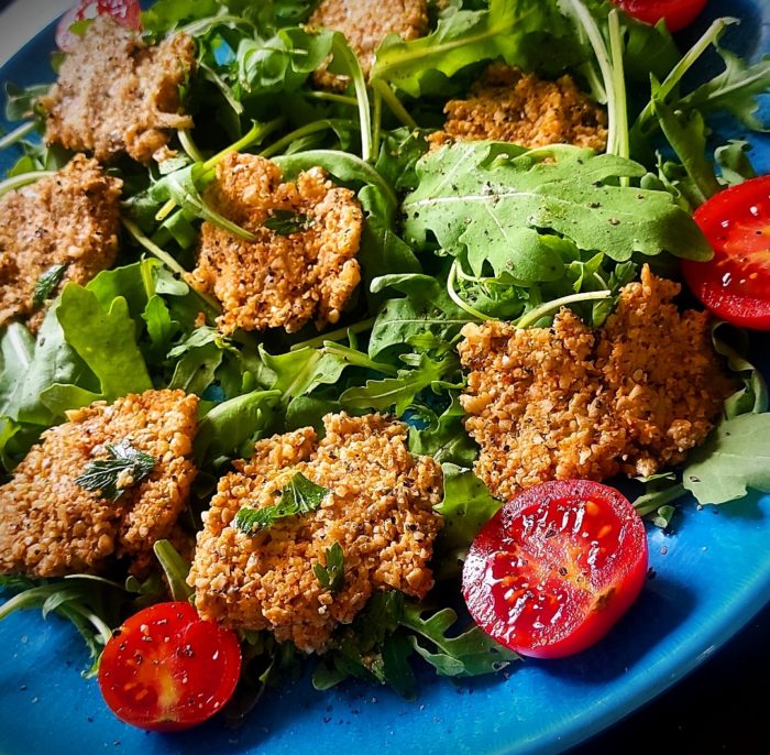 cauliflower bites surrounded by rucola and halved cherry tomatoes on a blue plate