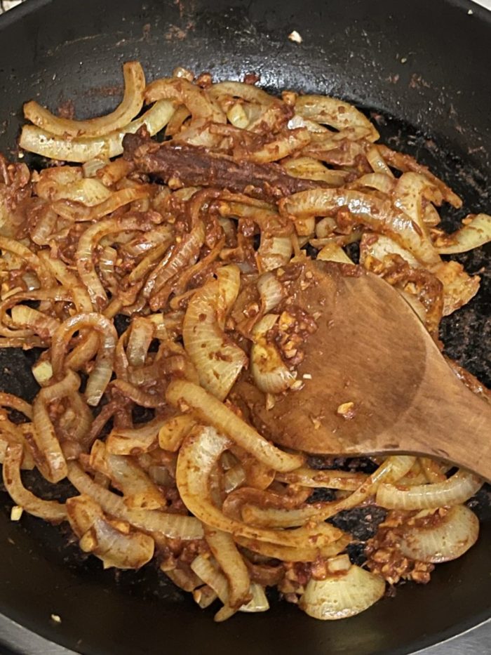 vegan biryani in a dark pan with wooden spoon