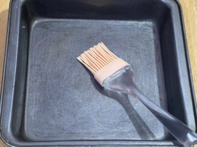 oil brush in a dark square pan