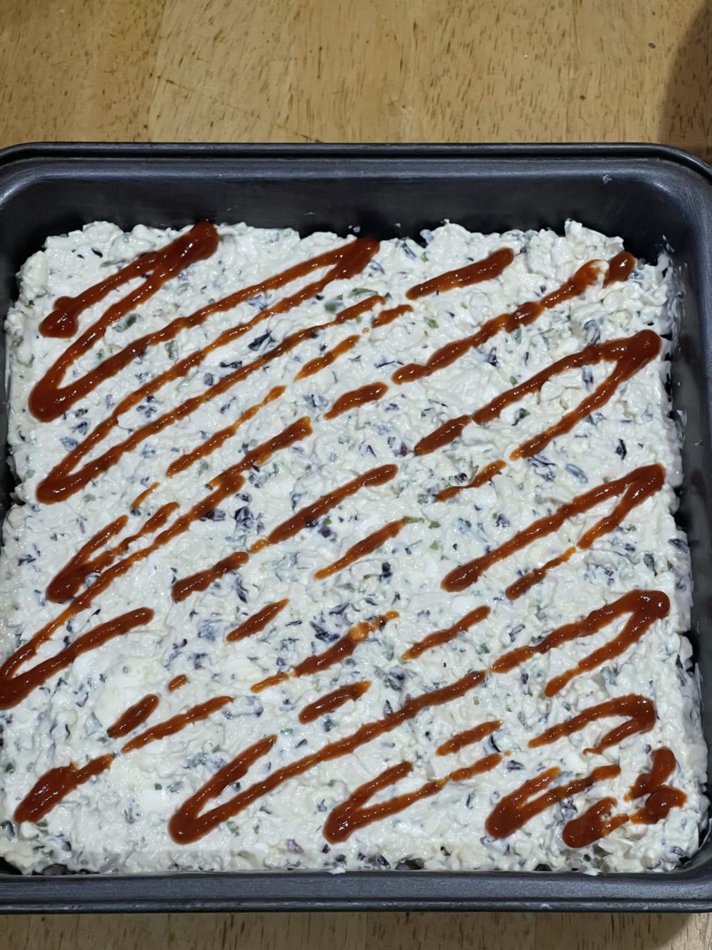 vegan sushi bake in a dark square pan on a wooden tabletop