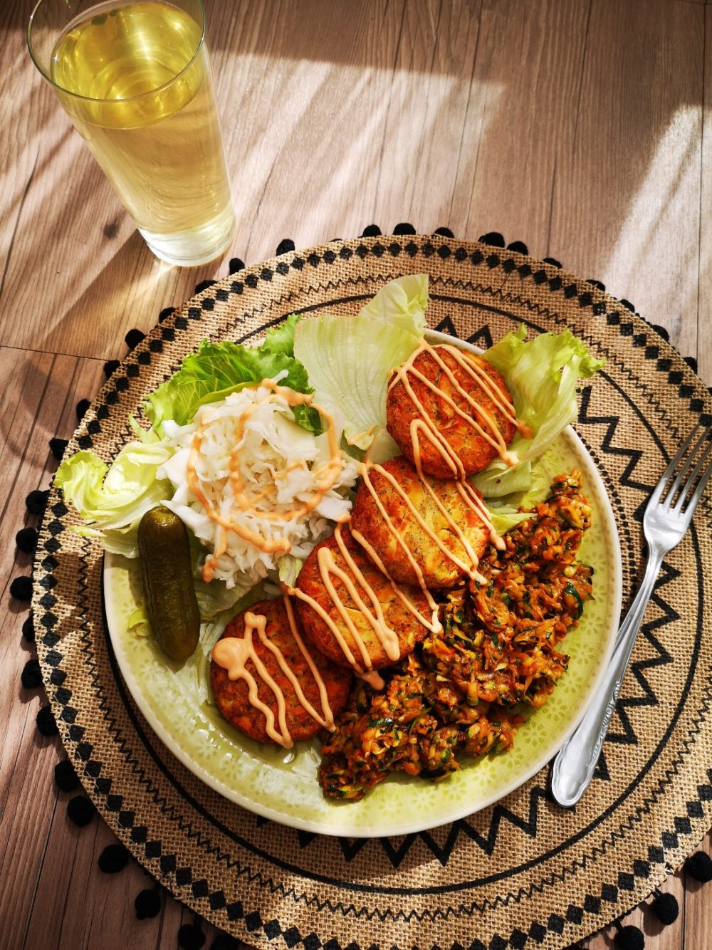 aruk patties on a light green plate on a decorative placemat with a fork, next to a glass