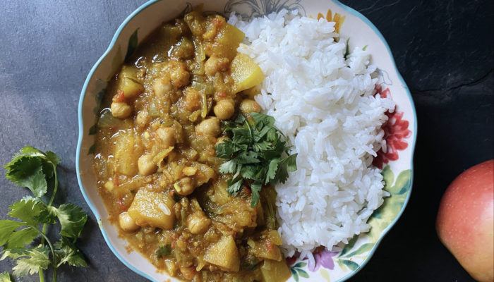 vegan apple chickpea curry and white rice in a floral dish against a black background