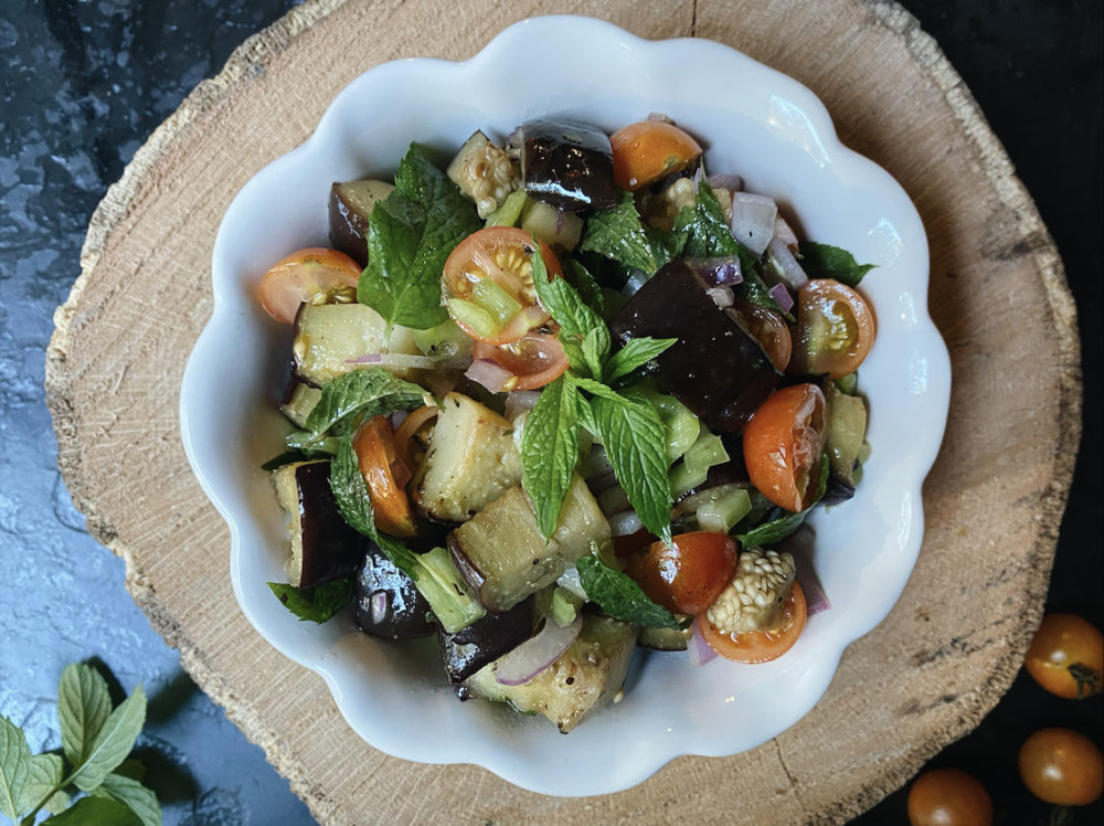 roasted eggplant salad in a white dish against a brown and black background