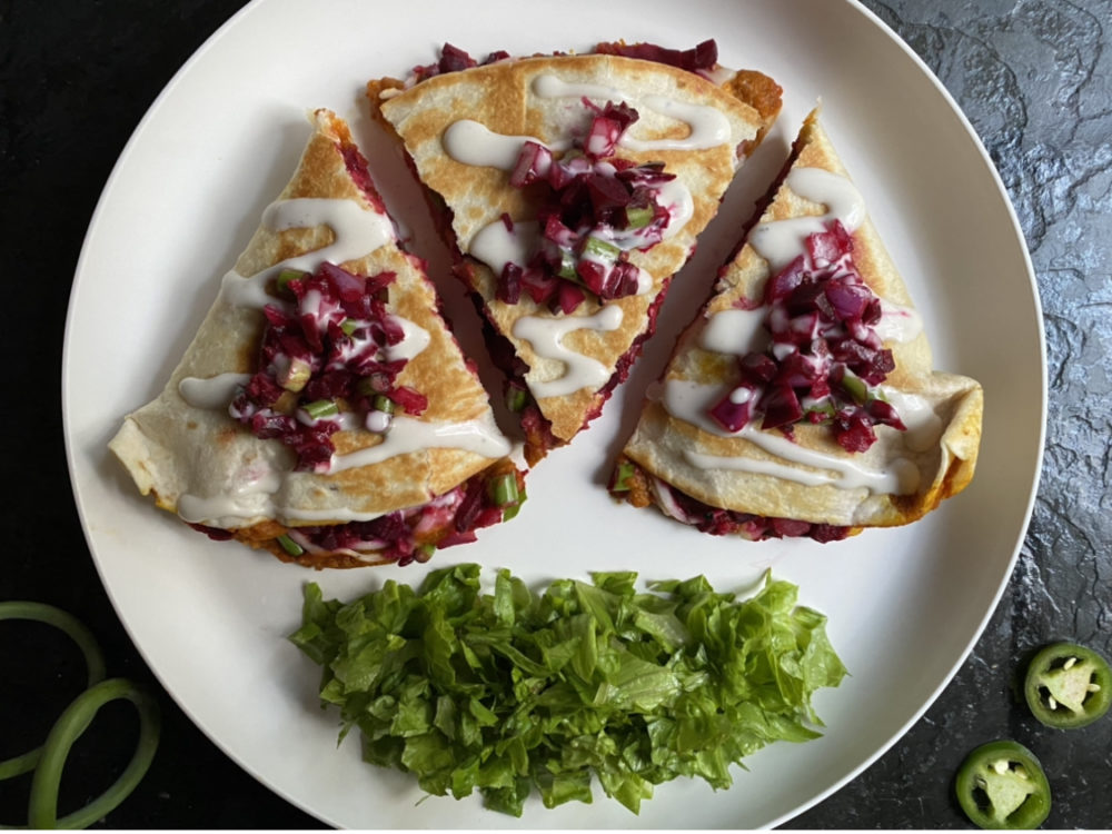 vegan pumpkin quesadillas and greens on a white plate against a dark background