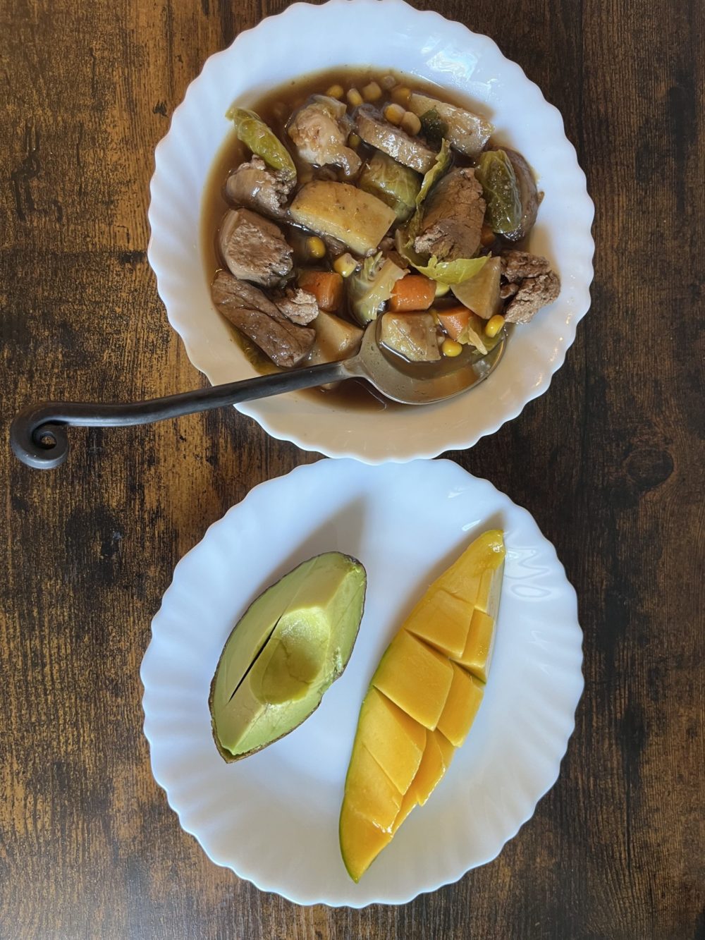 vegan jerk chicken in a white bowl; fruits on a white dish against a wooden background