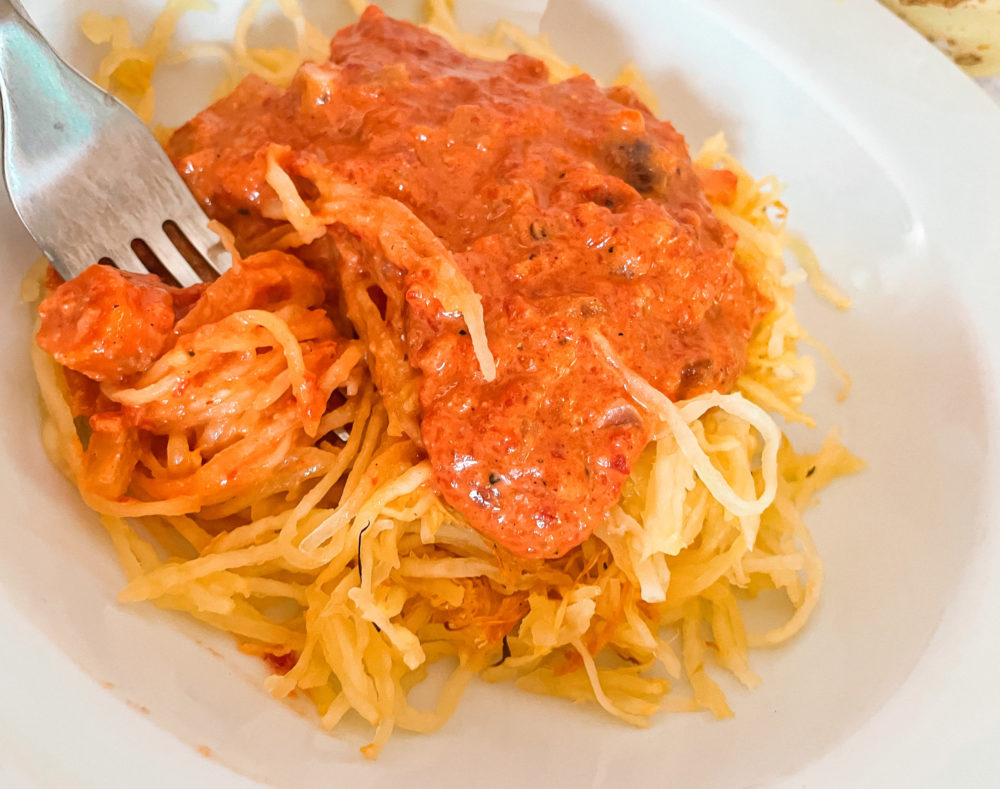 roasted red pepper squash noodles in a white dish with a silver fork