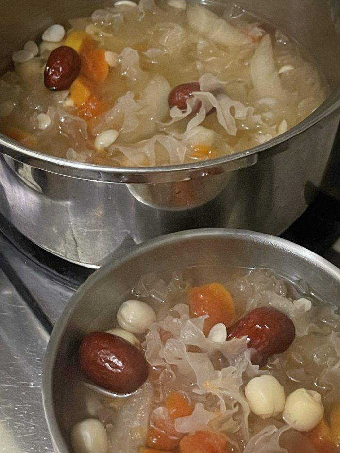 soup ingredients cooking in two silver pots