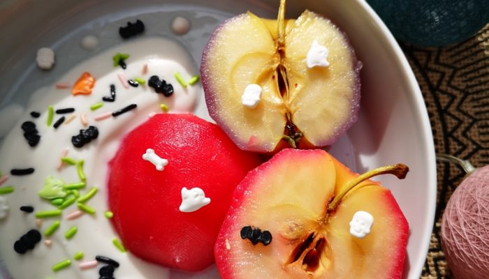 poached apples and sprinkles in a white bowl with decorations in the background