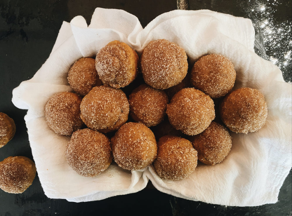 vegan baked pumpkin donut holes on white material against a black background