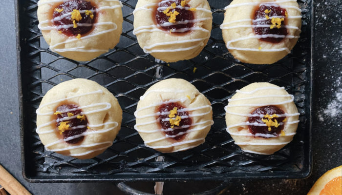 vegan cranberry orange thumbprint cookies on a black cooling rack