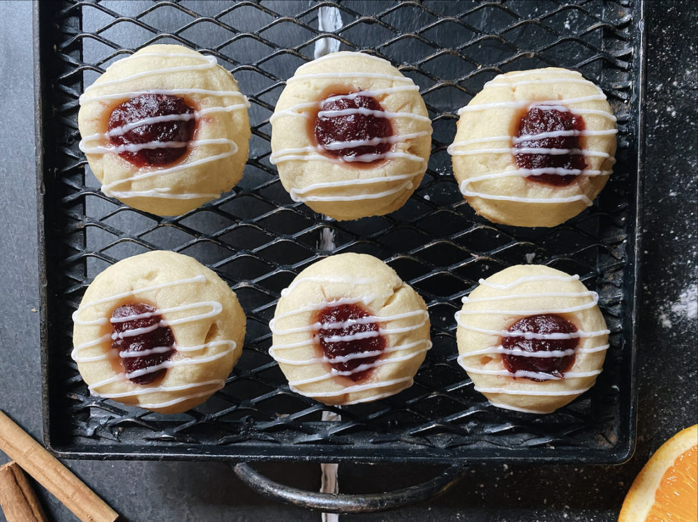 vegan cranberry orange thumbprint cookies on a black cooling rack