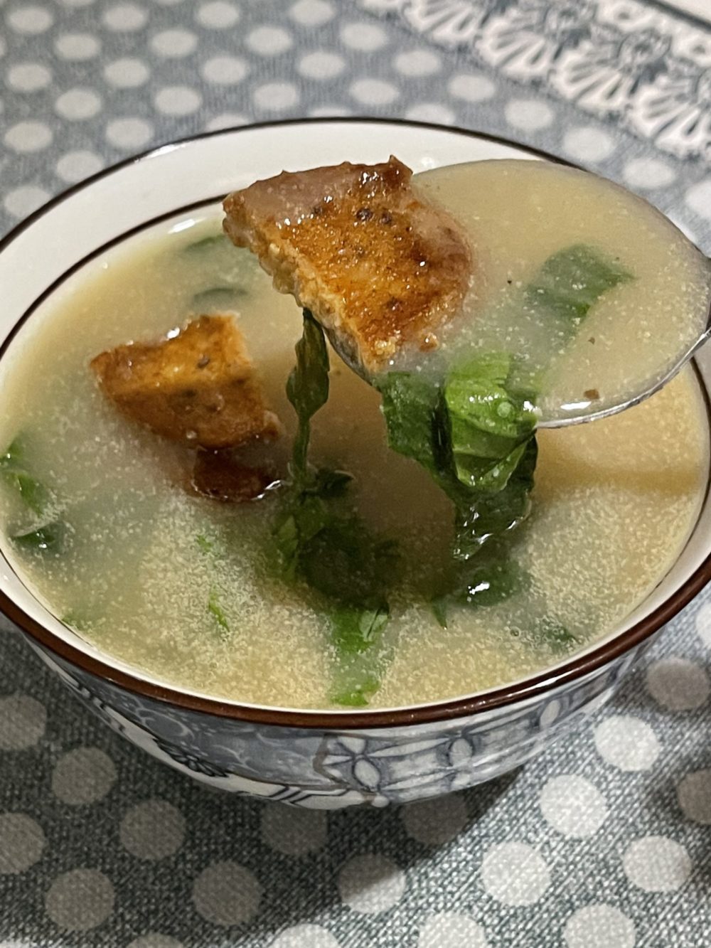 a spoonful of vegan caldo verde soup in front of a soup bowl