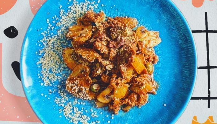 vegan meaty stew on a blue plate against a decorative background