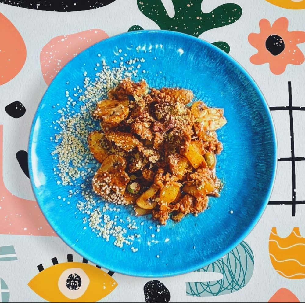 vegan meaty stew on a blue plate against a decorative background