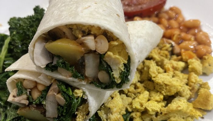 a vegan breakfast wrap cut in half, on a white plate