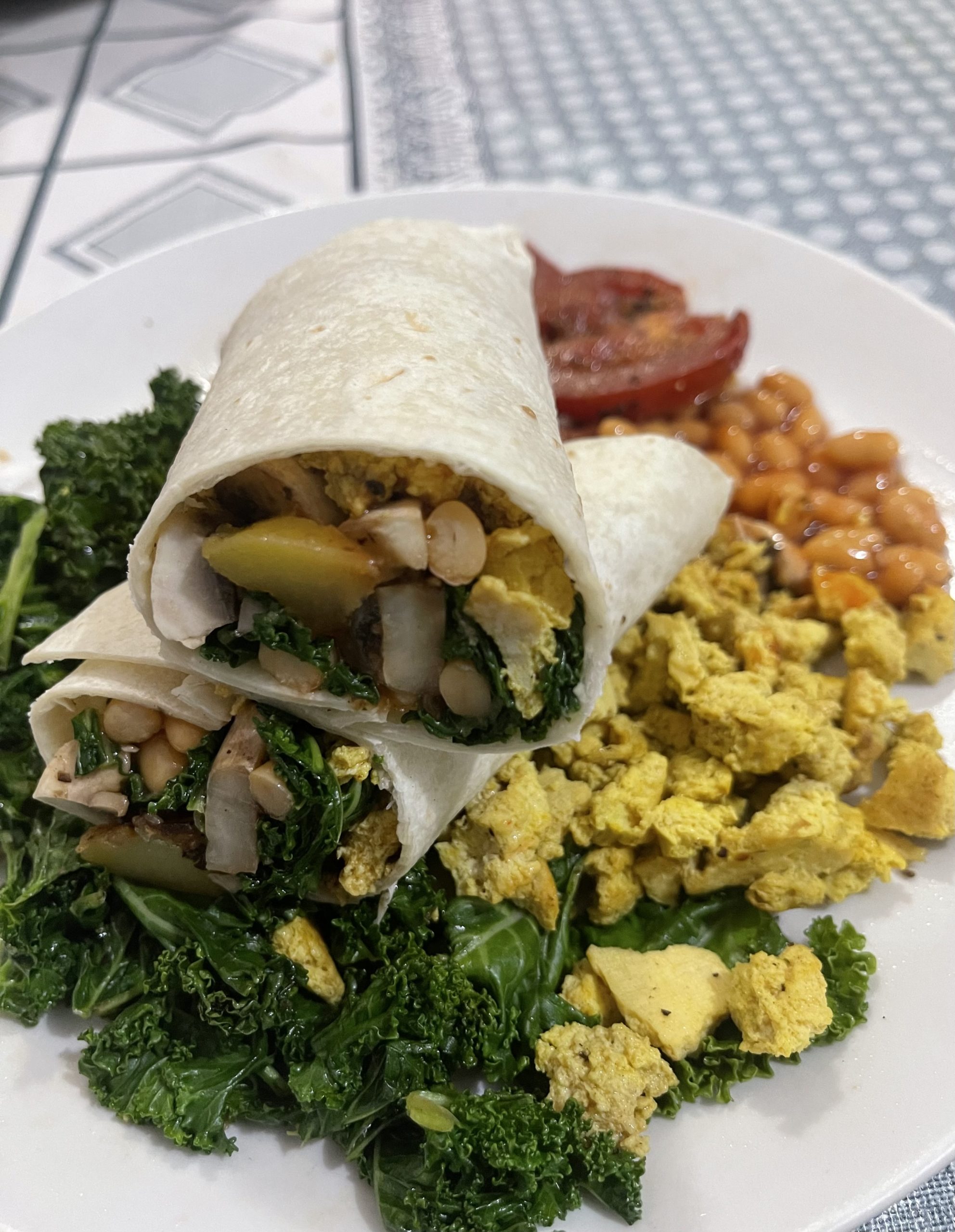 a vegan breakfast wrap cut in half, on a white plate