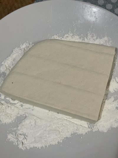 a block of tofu and flour on a white plate