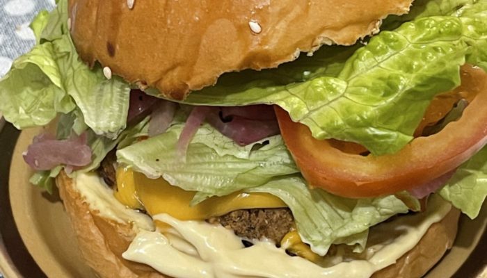 a vegan krabby patty burger on a plate against a blue polka dot background