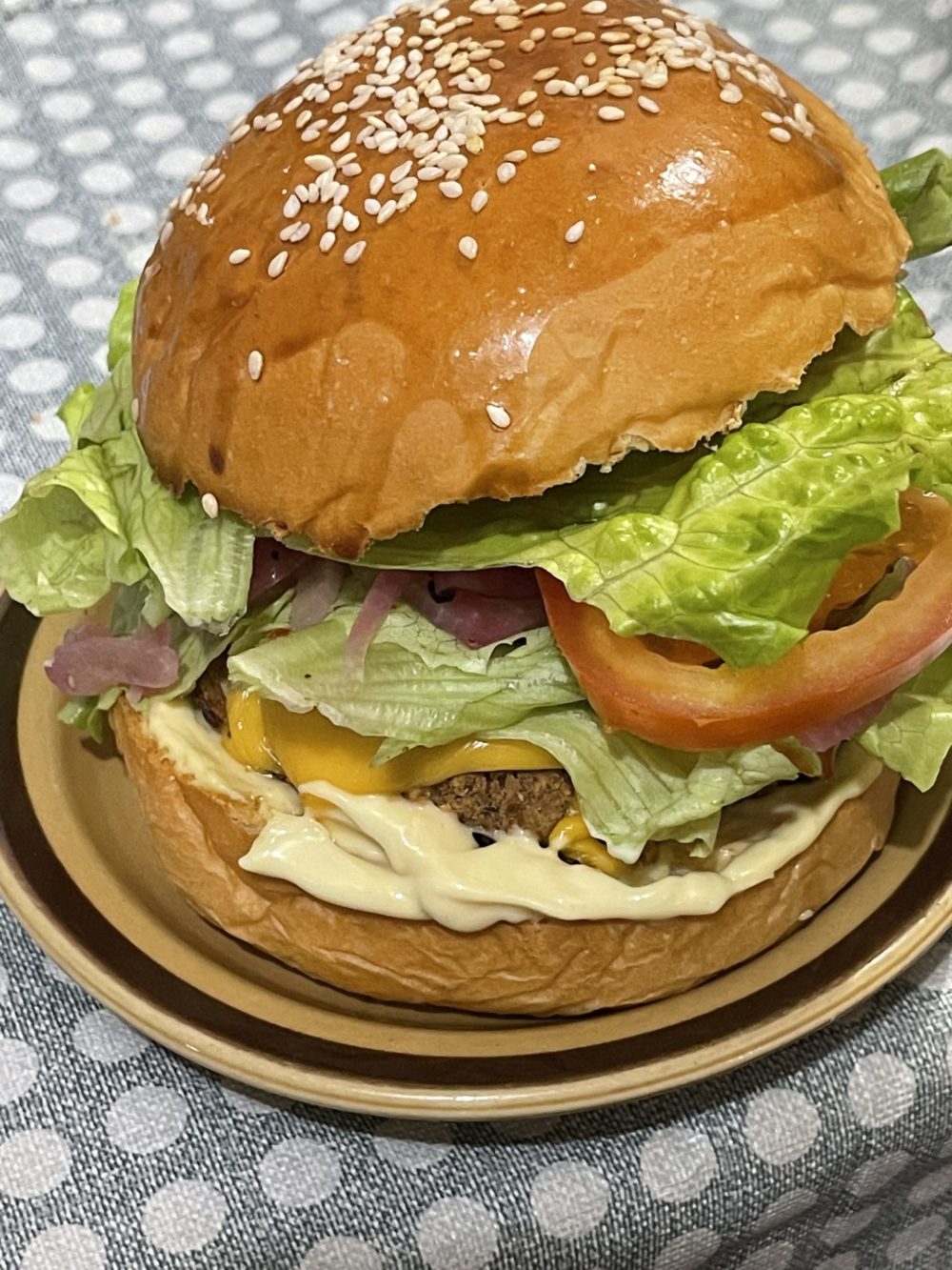 a vegan krabby patty burger on a plate against a blue polka dot background