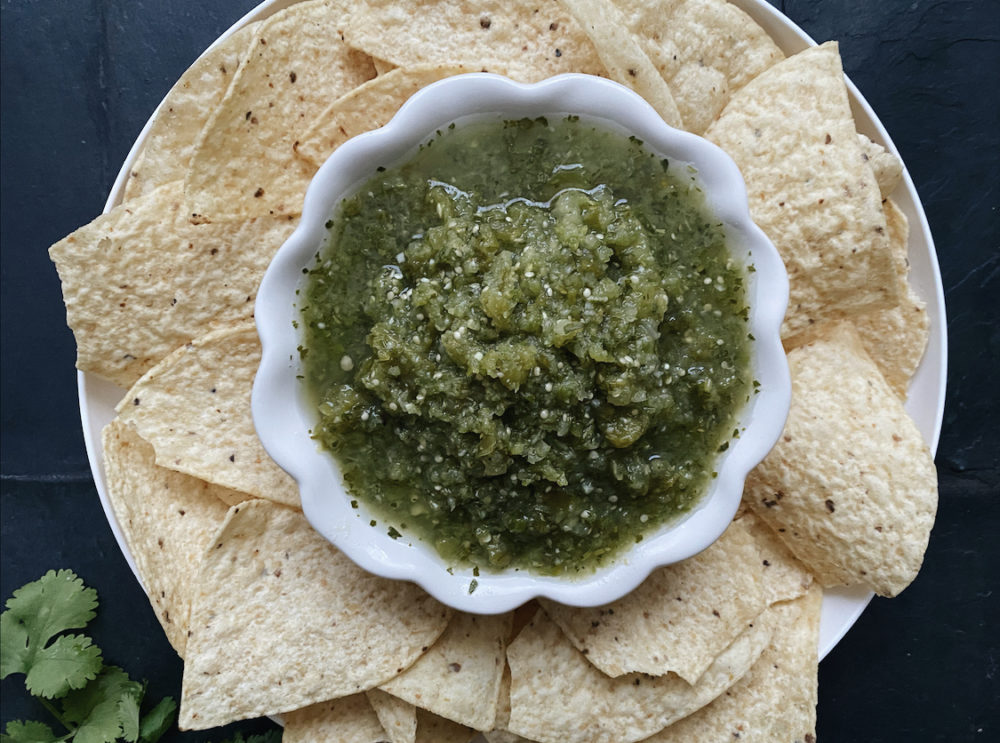 classic salsa verde and chips against a dark background