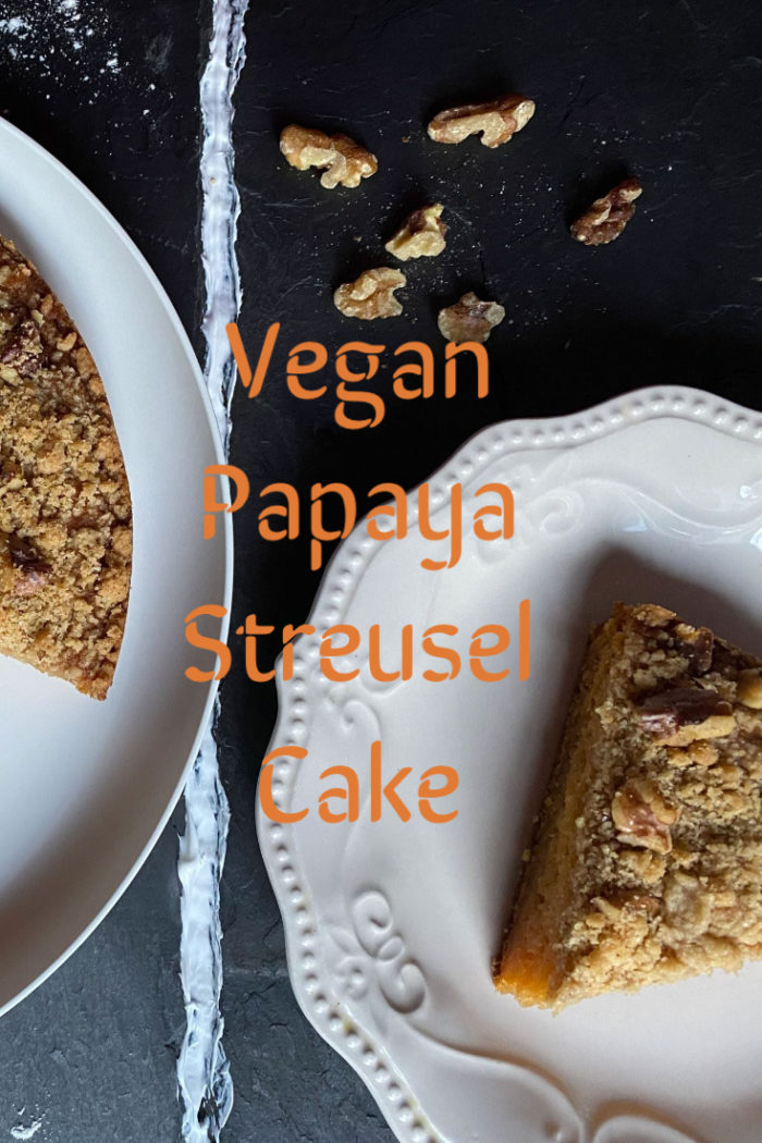 vegan papaya streusel cake on white plates against a dark background