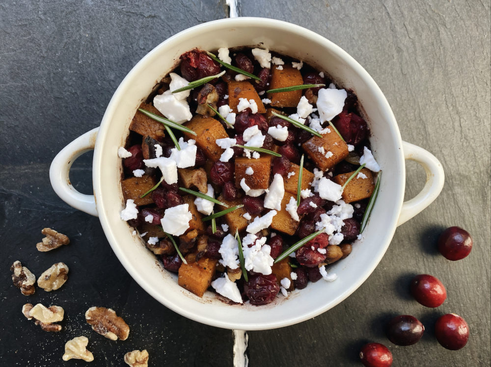 roasted pomegranate cranberry squash in a white bowl against a dark background