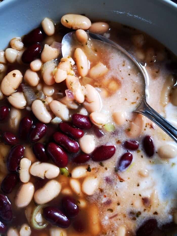 Bean soup in a light blue bowl with a silver spoon