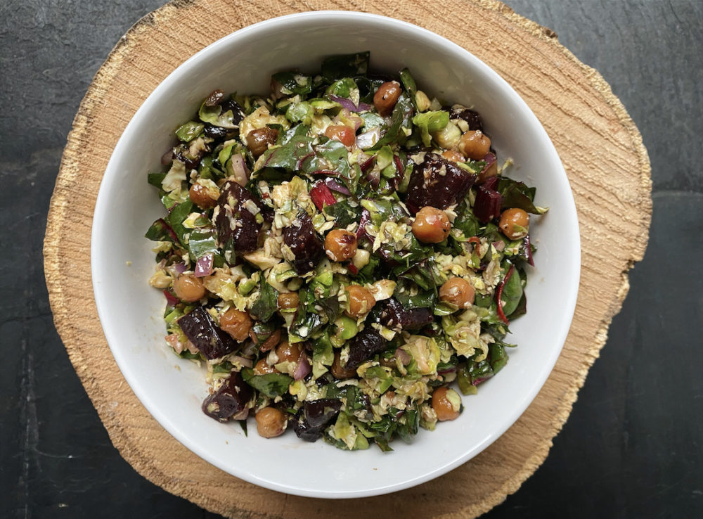 vegan chopped Brussels sprouts salad in a white bowl against a black background