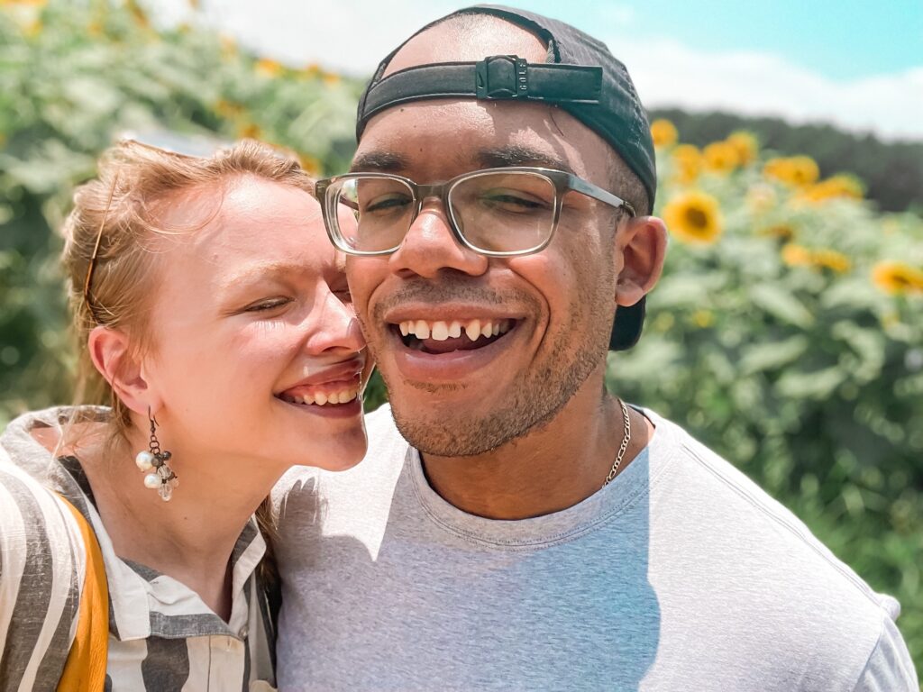 man and woman smiling in a sunflower field