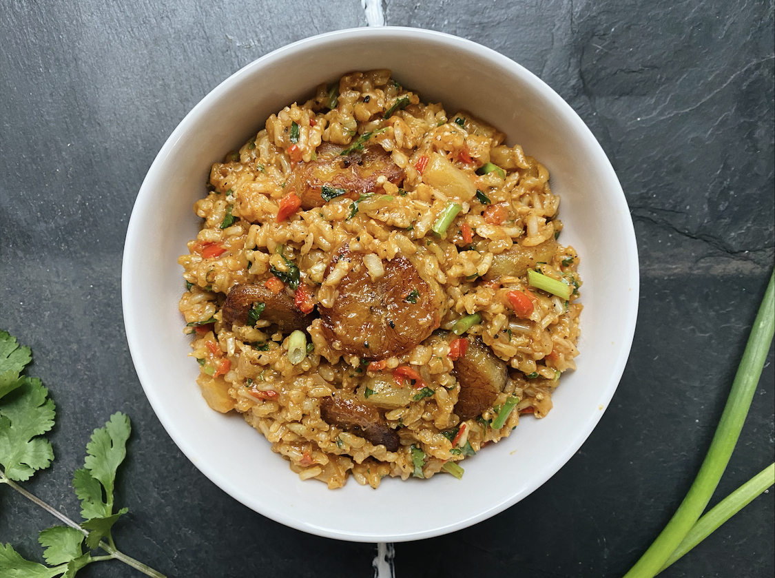 vegan pineapple paella with vegetables in a white dish against a black background