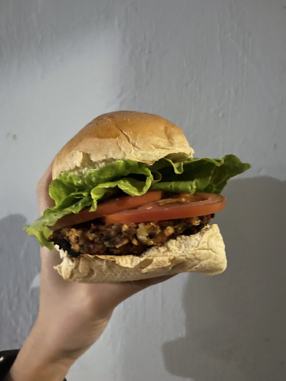 A vegan garden burger with lettuce and tomato against a white background