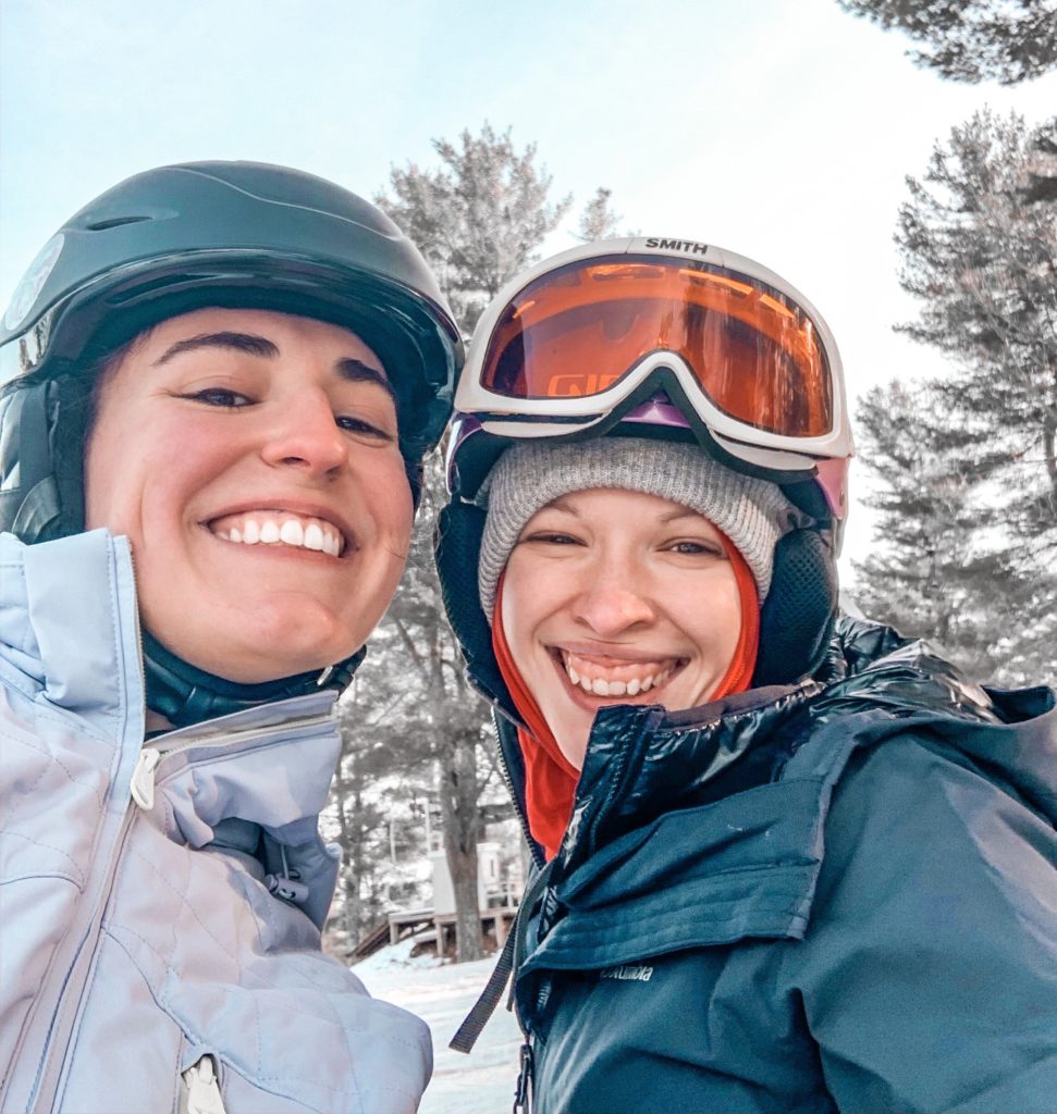 two woman smiling wearing ski gear