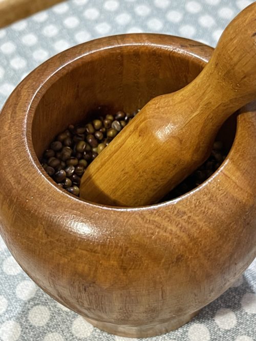 wooden mortar and pestle with mung beans.