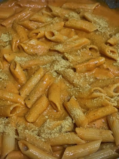 penne noodles coated in orange-colored vodka sauce and sprinkled with nutritional yeast.
