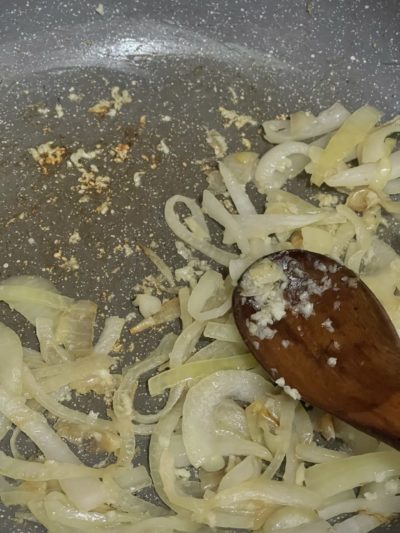 onion slices cooking in a pan and a spatula.